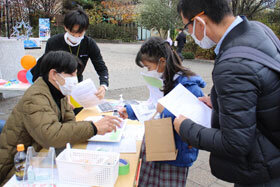 写真：説明書と材料キットを手渡す学生