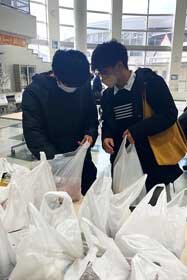 写真：食料品が詰まった袋を覗き込む学生たち