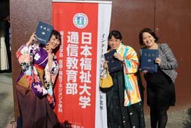 写真：日本福祉大学通信教育部の旗の前で記念撮影をする女学生たち