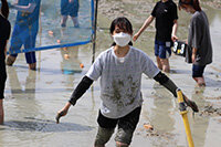 写真：泥んこになりながらバレーボールを楽しむ女性