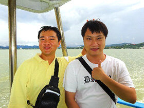 写真：船上でポーズを決める男子学生2人