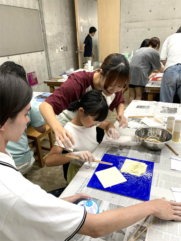 箔ばさみを使う子どもを見守る学生