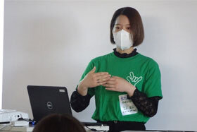 写真:緑のユニフォームTシャツを着て発表をする女学生