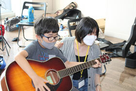 写真：大学生にギターを教わる小学生1