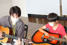 写真：大学生にギターを教わる小学生2