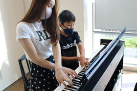 写真：大学生にピアノを教わる小学生